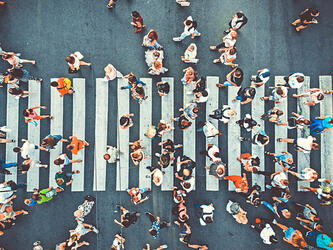 aerial view of dozens of pedestrians walking across a street crossing